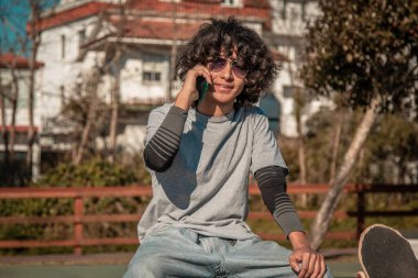 Kaykaylı ve cep telefonuyla konuşan Latin bir genç.