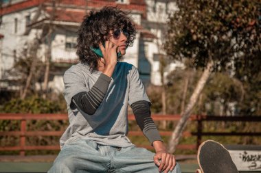 Kaykaylı ve cep telefonuyla konuşan Latin bir genç.