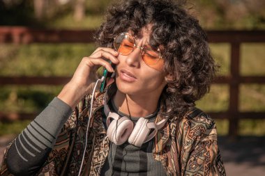 Genç afro saçlı adam cep telefonuyla konuşuyor.