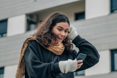 Sokakta telefonu olan genç bir kız ve şaşkınlık ifadesi.