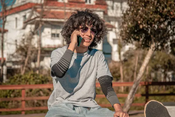 Junger Mann Sitzt Mit Skateboard Und Telefoniert Auf Der Straße — Stockfoto