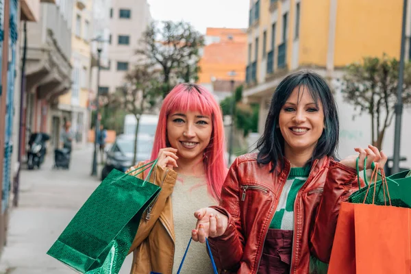 happy female friends shopping with bags on the street