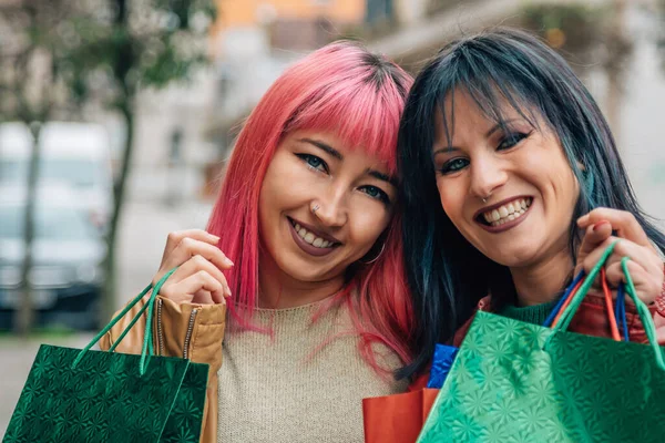 couple of girls in love shopping with bags on the street