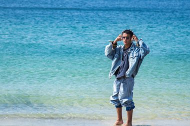 Plajda kulaklıklı rahat bir adam.