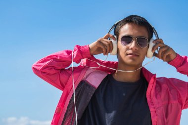 Dışarıda kulaklıkları olan rahat bir genç adam.