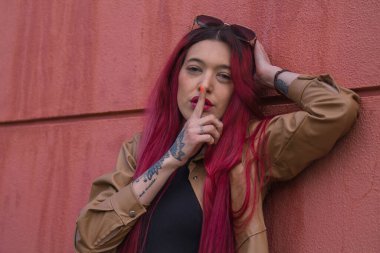 Genç bir kadın sokak duvarında parmak işareti yapıyor.