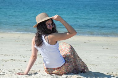 Kumsalda şapkalı rahat bir kız. 