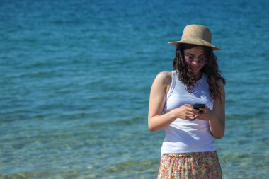 Kız sahilde telefonla konuşuyor.