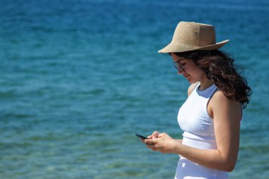 Şapkalı kız plajda mesaj yolluyor.