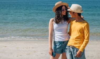 Birbirine aşık çiftler sahilde yürüyor.