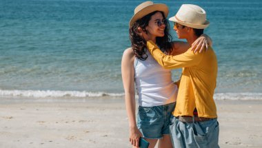 Düğün çifti sahilde mutlu bir şekilde sarılıyor.