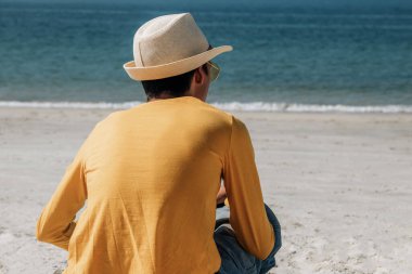 Genç Latin Latin adam plajda dinleniyor ve denize bakıyor.