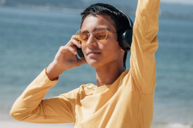 Plajda kulaklıklı rahat bir adam.