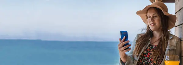 stock image tourist woman with mobile phone at the beach bar with sea background