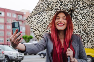 Şemsiyeli ve cep telefonlu etkili kız canlı video çekiyor.