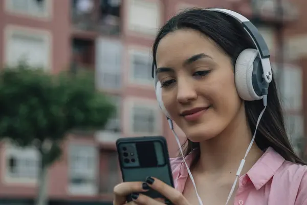 smiling young woman with headphones on the street