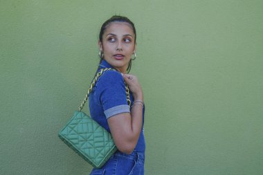 Latin kadın kotu ve çanta yeşil duvarda.