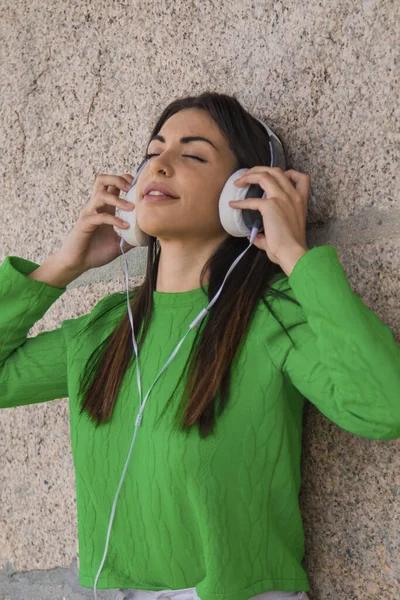 relaxed latin hispanic young woman with headphones on the street