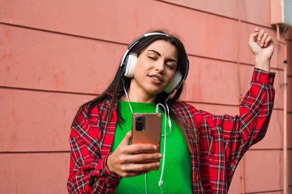 relaxed young woman with headphones and phone on the street