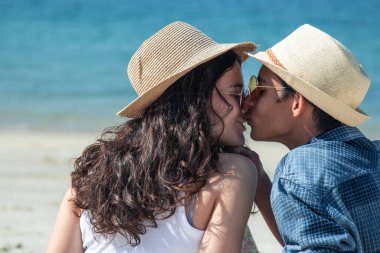 Düğün çifti sahilde mutlu öpüşüyor.