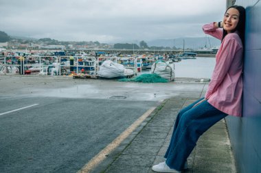 Gülümseyen genç kadın duvara yaslanıyor.