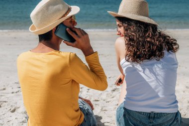 Sahilde cep telefonu olan çift.