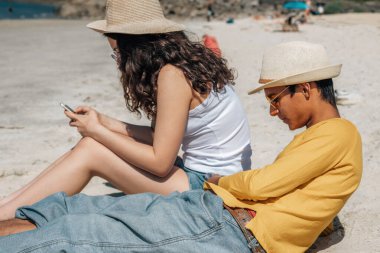Sahilde cep telefonu olan bir çift.