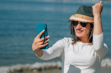 Zaferi olan genç bir kadın ya da kumsalda telefonla yapılan başarılı bir jest.