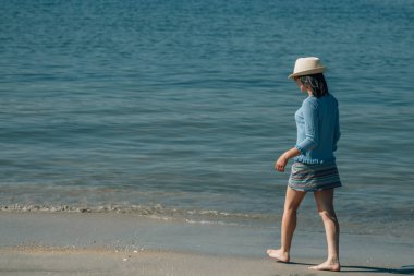 Kumsalda yürüyen rahat genç bir kadın.