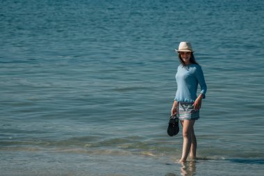 Kumsalda yürüyen rahat genç bir kadın.