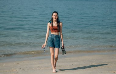 Gülümseyen kız sahilde yürüyor