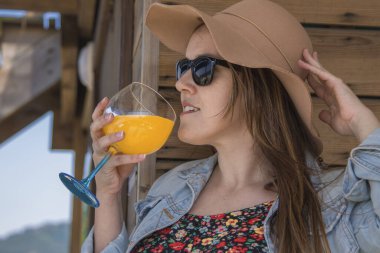 Plaj barının terasında kokteyl içen gevşemiş bir kadın.