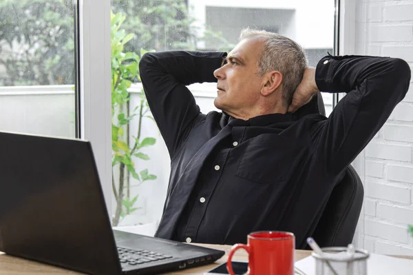 relaxed businessman in office chair looking out the window