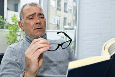Gözlüklü, miyop ya da kitap okuyan olgun bir adam.