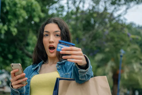 girl with credit card and phone with shopping bags on the street