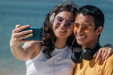 Sahilde telefonlu gençler selfie çekerken eğleniyorlar.