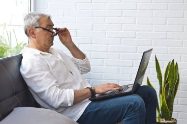 Bilgisayarla çalışan gözlüklü ve miyoplu orta yaşlı bir adam.