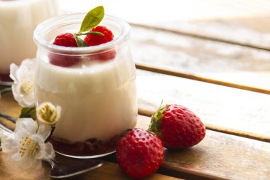 Ahşap arka planda çilekli doğal yoğurt.