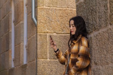 Sonbaharda duvarında telefonu olan genç bir kadın.