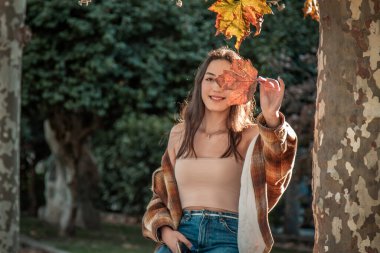 Sonbahar arka planında kuru sonbahar yaprağı olan genç bir kadın.