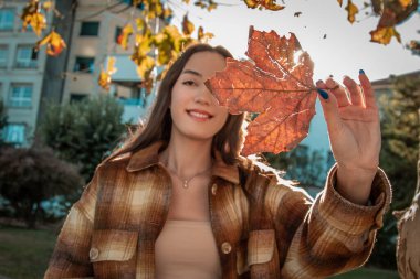 Sonbahar akçaağaç yaprağıyla sonbahar arka planında genç bir kadın