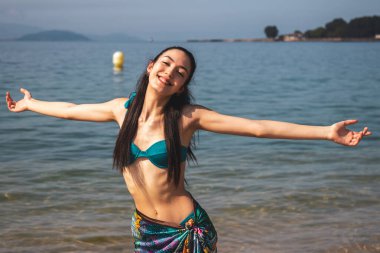 Özgür, mutlu, kolları kumsalda yükselmiş temiz hava soluyan bir kız.