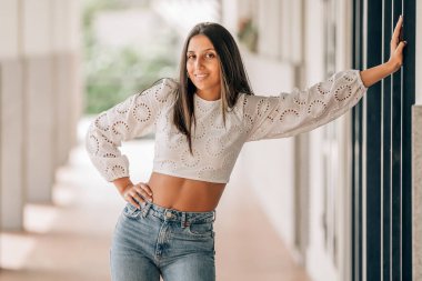 Gülümseyen güzel kadın duvarda poz veriyor.