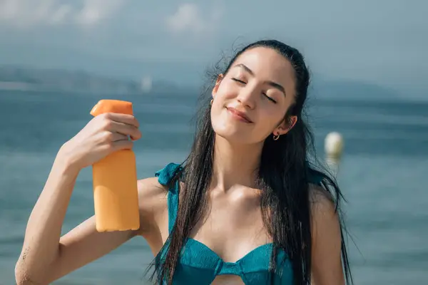 girl on the beach applying sun tanning cream