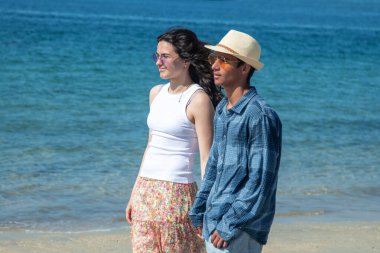 Düğün çifti kumsalda el ele yürüyor.