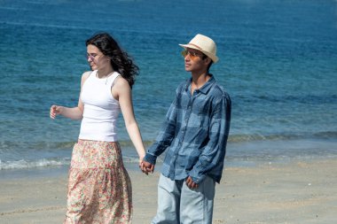 Düğün çifti kumsalda el ele yürüyor.