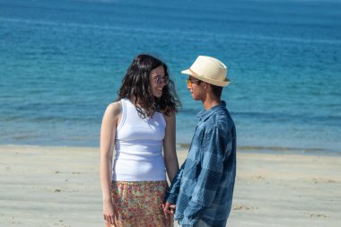 Düğün çifti kumsalda el ele yürüyor.