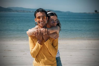 Kulaklıklı, kumsalda eğlenen rahat genç bir çift.