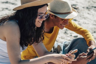 Gençler sahilde akıllı telefon kullanıyor.