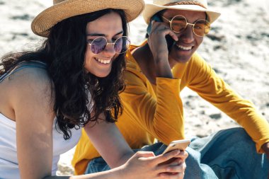 Gençler sahilde akıllı telefon kullanıyor.